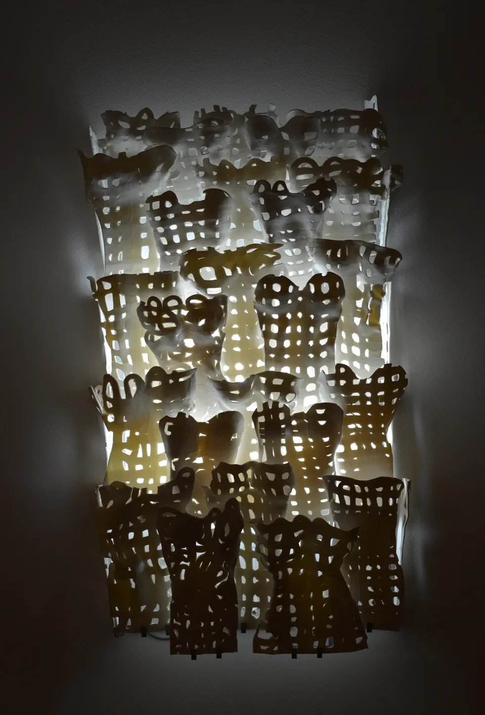Corsets, panneau mural composé de modules de porcelaine ajourés rétro-éclairés d’une lumière blanche.